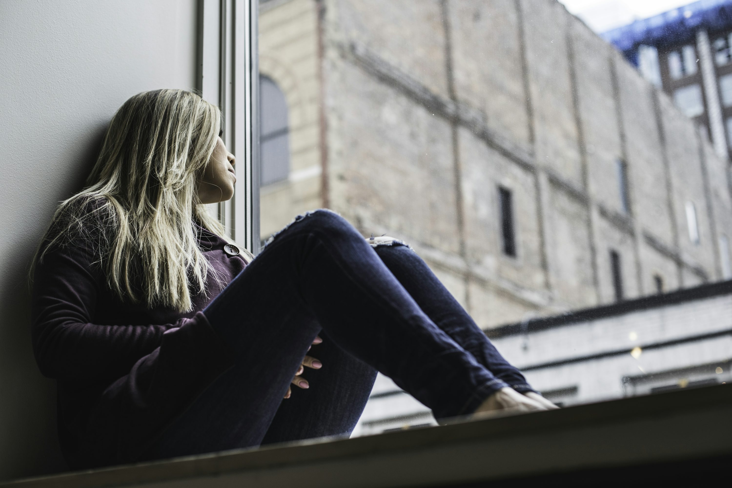 A person sitting by a window and looking out at the city.