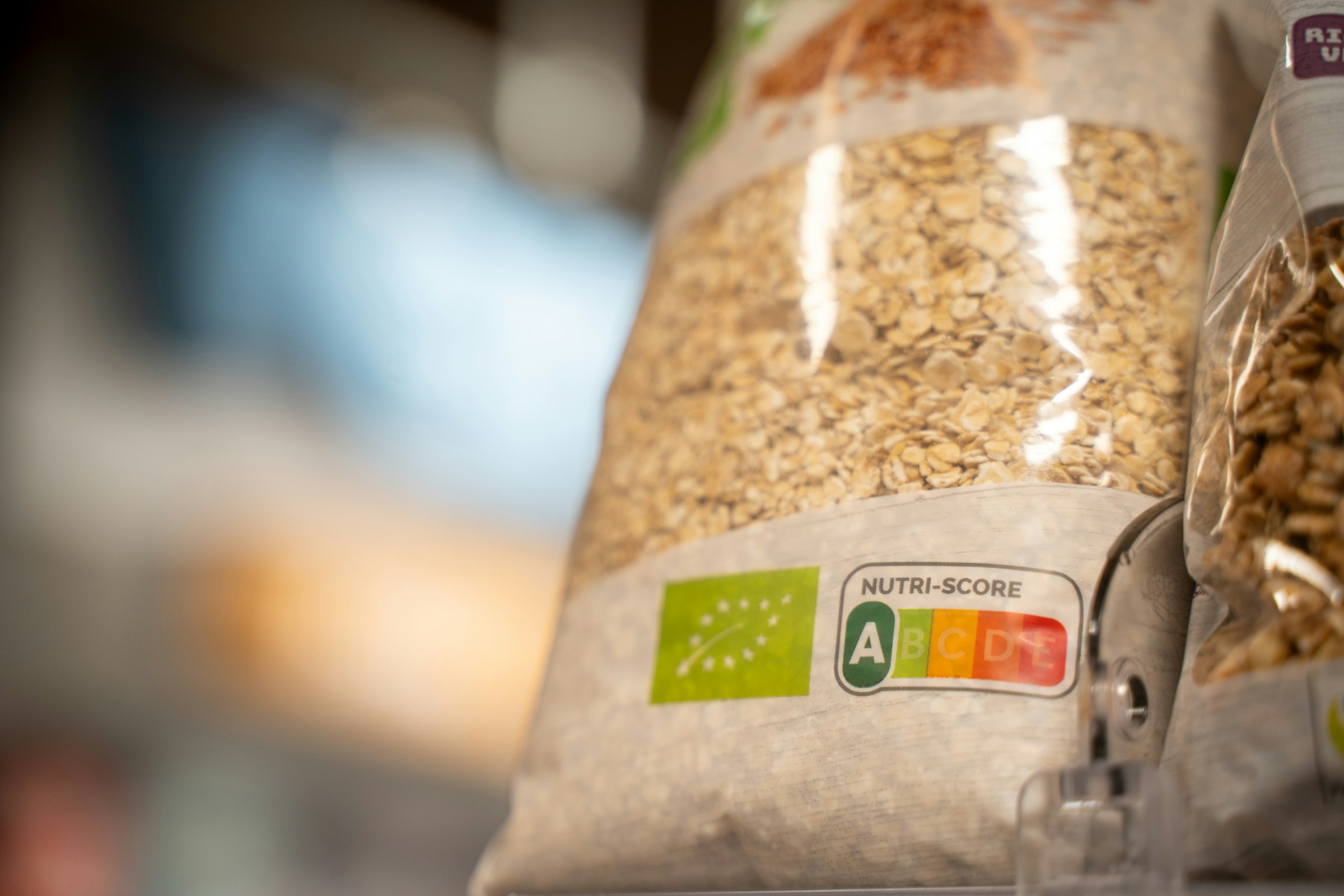 A bag of oats on a supermarket shelf showing a colour-coded Nutri-Score label and an organic certification mark.